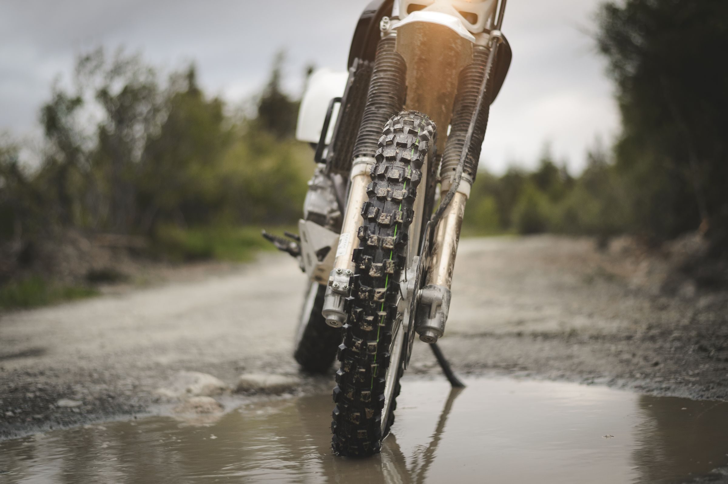 Pneu avant à crampons d’une moto tout-terrain sur un chemin mouillé